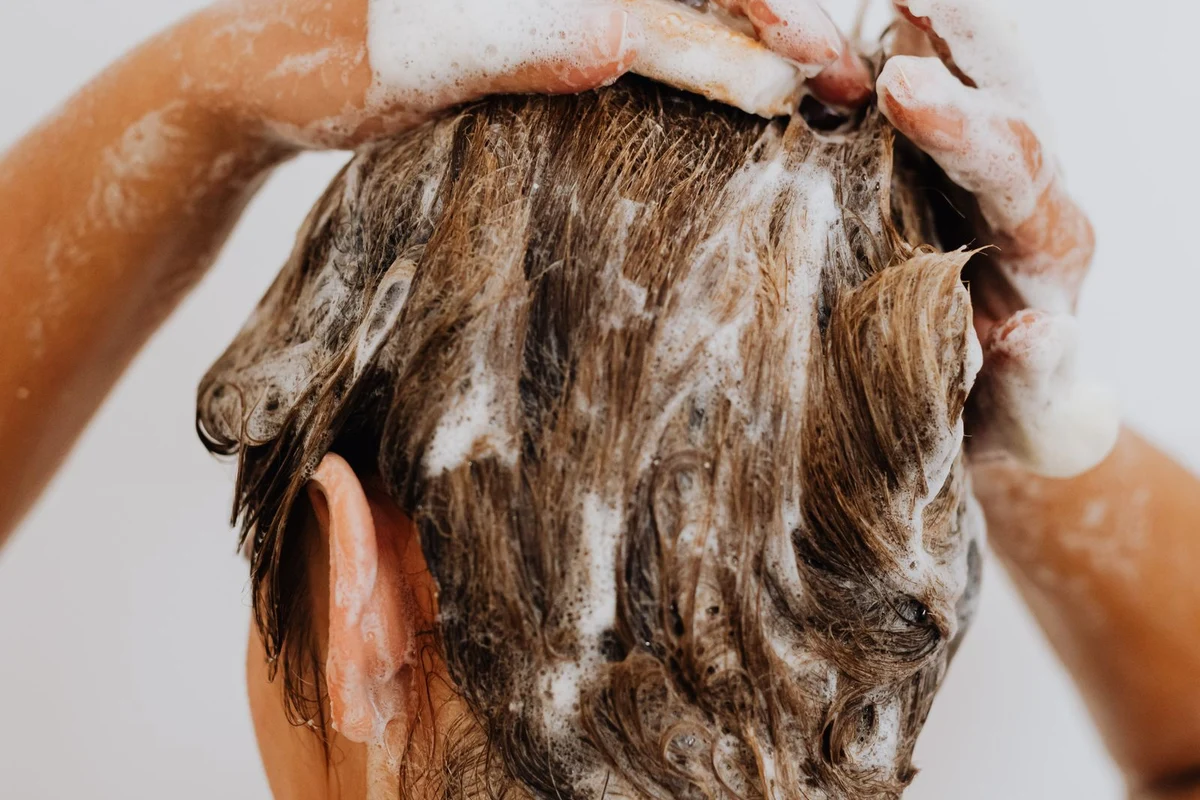 Person thoroughly shampooing hair and scalp to remove product buildup