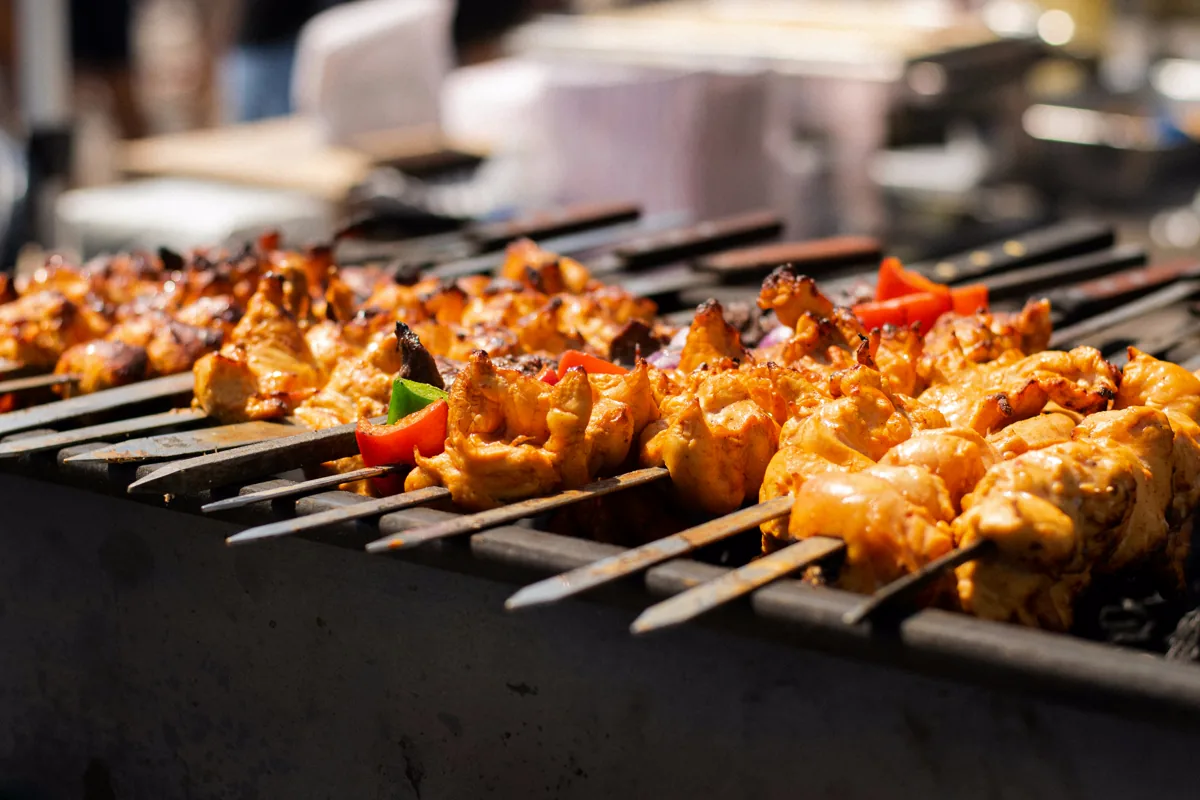 Chicken and vegetable kebabs cooking over a hot grill.