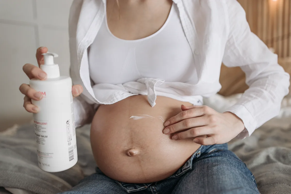 Pregnant woman applying moisturizer to her abdomen