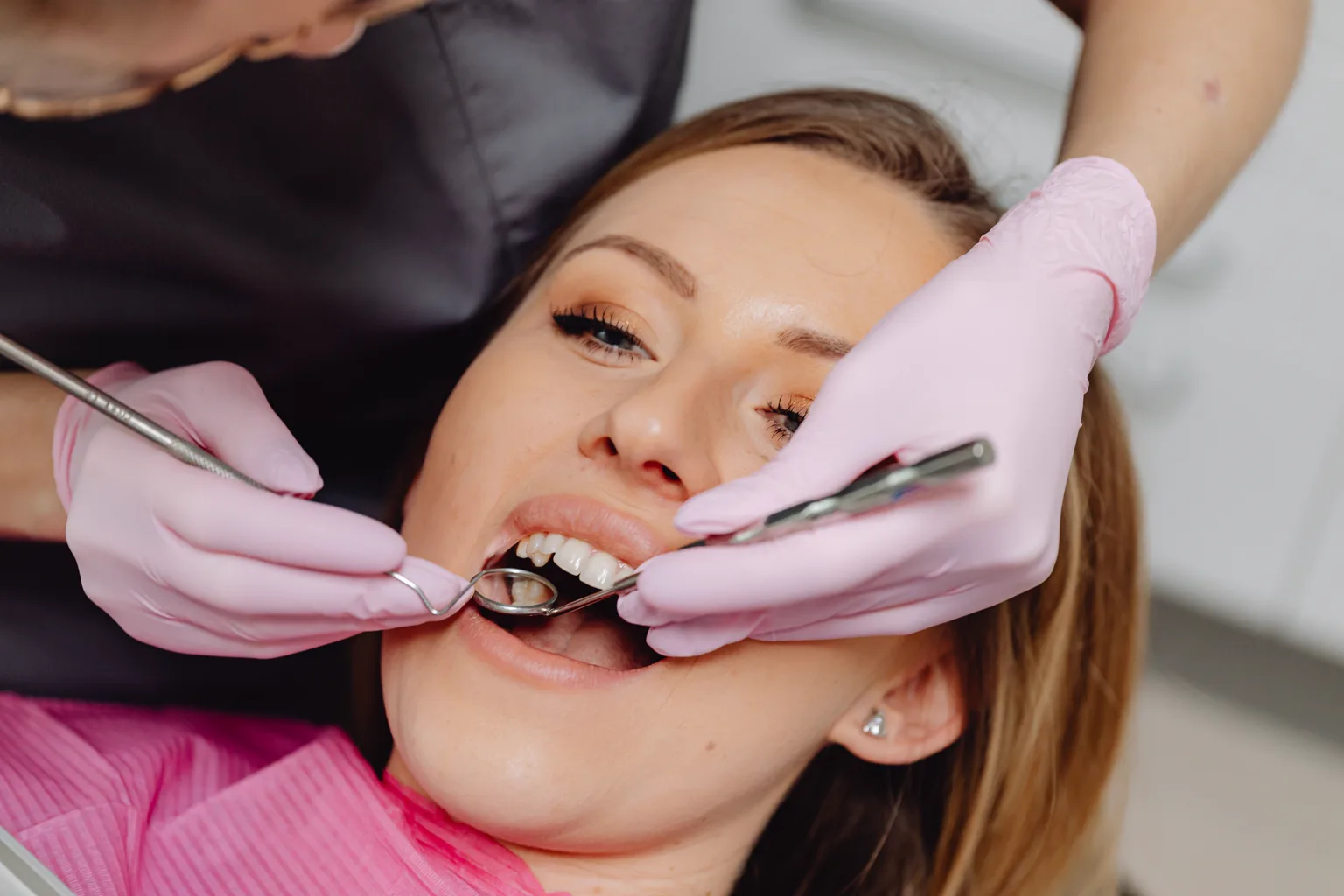 Dental professional examining a patient's teeth and gums with a mirror