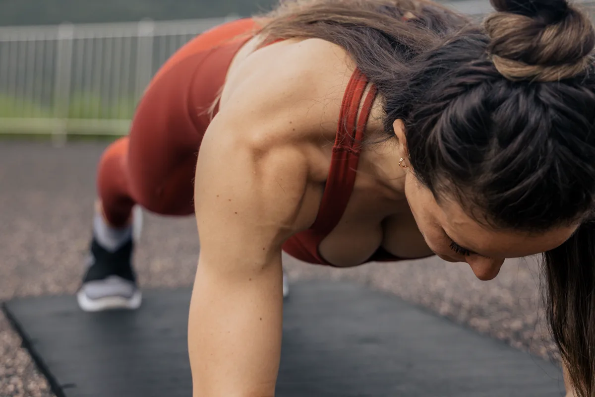 Woman performing a controlled plank exercise outdoors