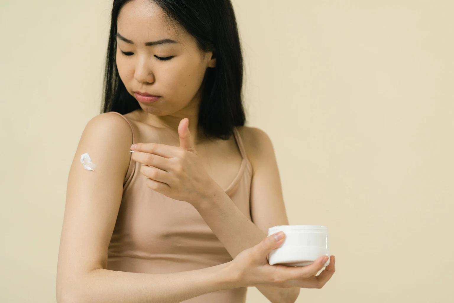 Woman applying moisturizer to the skin on her upper arm