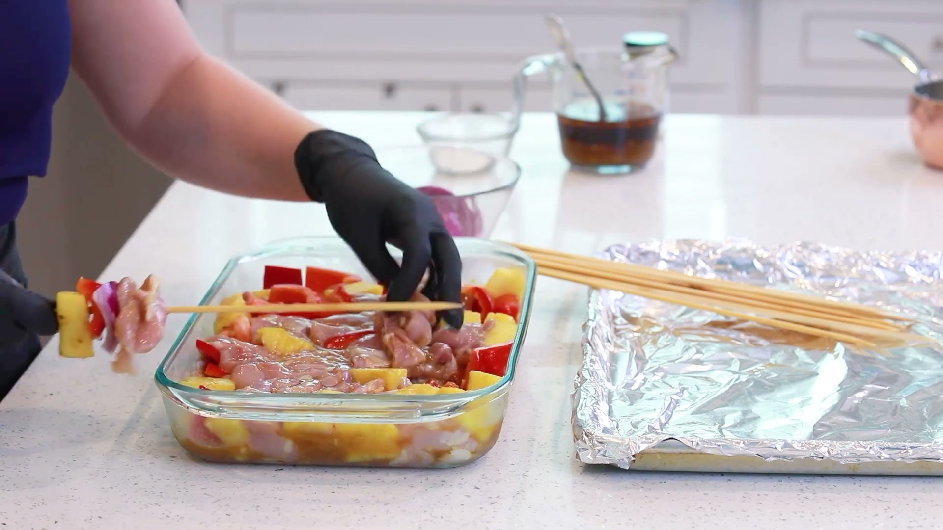 Threading chicken, pineapple, bell pepper, and onion onto wooden skewers