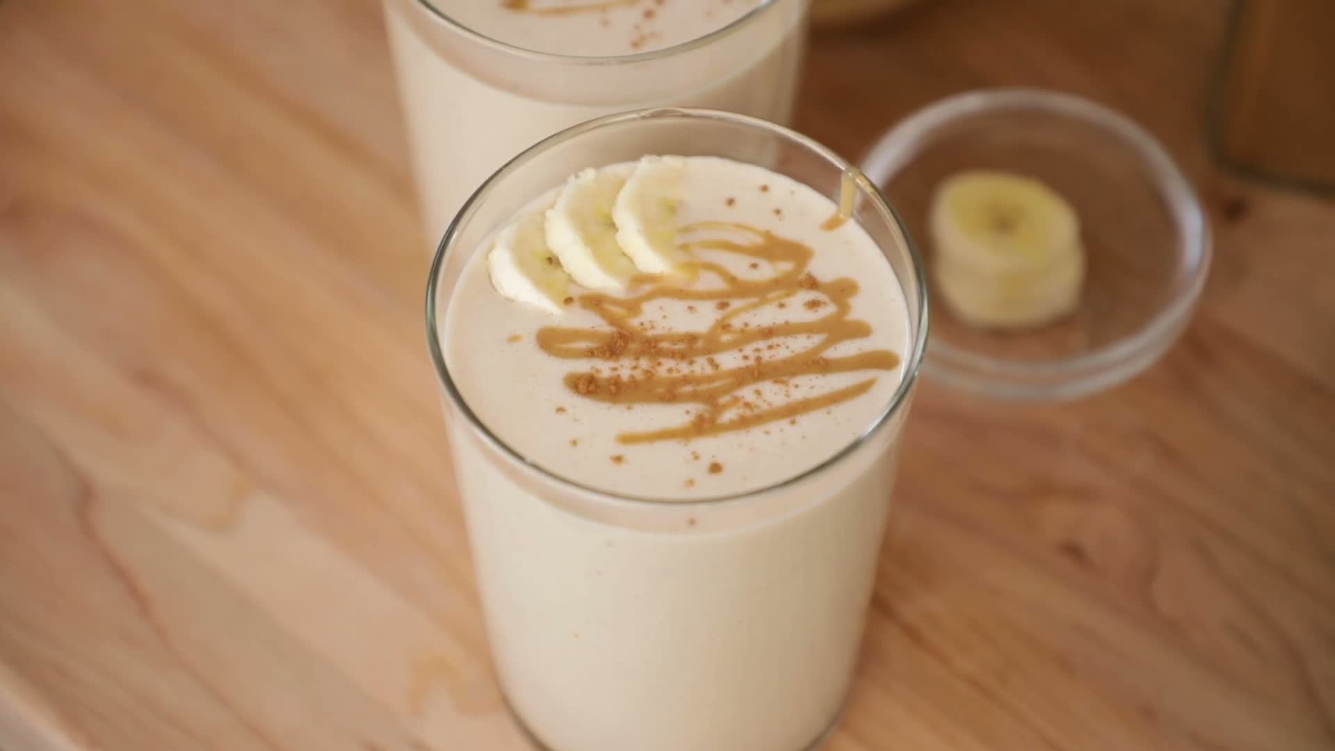 Finished banana peanut butter smoothie with banana slices and peanut butter drizzle