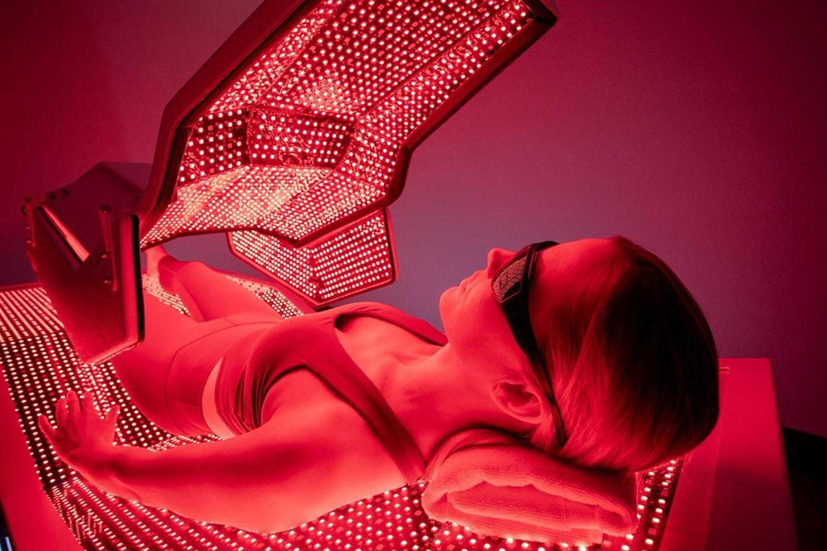 Person lying beneath a red light therapy panel during treatment